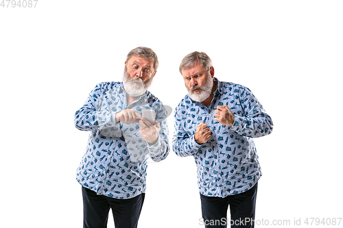 Image of Senior man arguing with himself on white studio background.