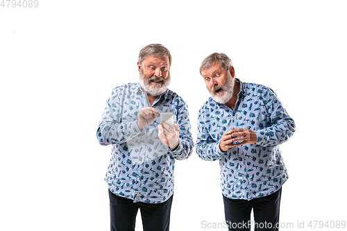 Image of Senior man arguing with himself on white studio background.