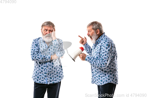 Image of Senior man arguing with himself on white studio background.