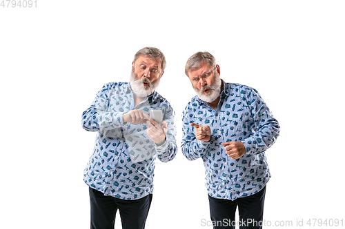 Image of Senior man arguing with himself on white studio background.