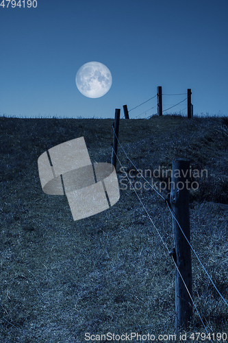 Image of moon over a hill and a fence