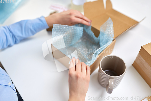 Image of hands packing mug to parcel box at post office