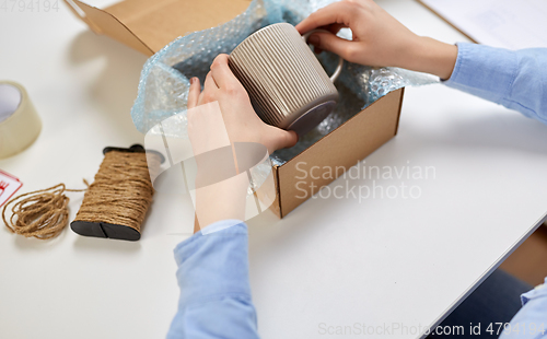 Image of hands packing mug to parcel box at post office