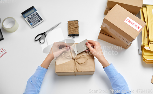 Image of hands tying name tag to parcel box at post office