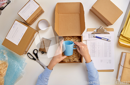 Image of hands packing mug to parcel box at post office