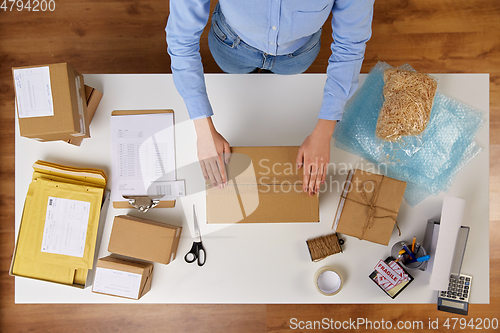 Image of woman packing parcel box with adhesive tape