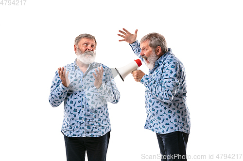 Image of Senior man arguing with himself on white studio background.