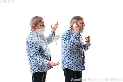 Image of Senior man arguing with himself on white studio background.