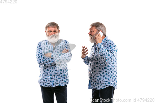 Image of Senior man arguing with himself on white studio background.