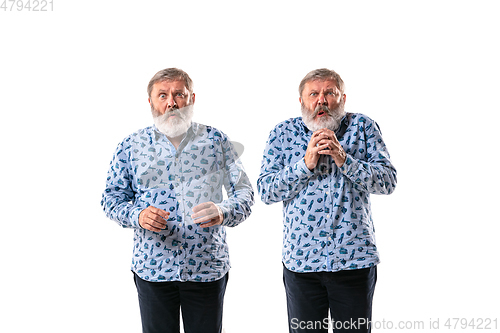 Image of Senior man arguing with himself on white studio background.