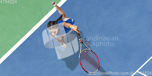 Image of Young woman in blue shirt playing tennis. Youth, flexibility, power and energy.