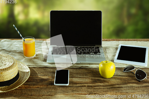 Image of Blank laptop on a wooden table outdoors, mock up