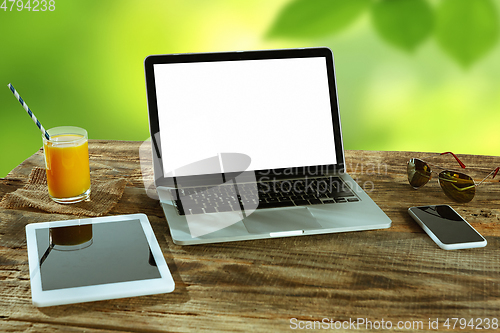 Image of Blank laptop on a wooden table outdoors, mock up