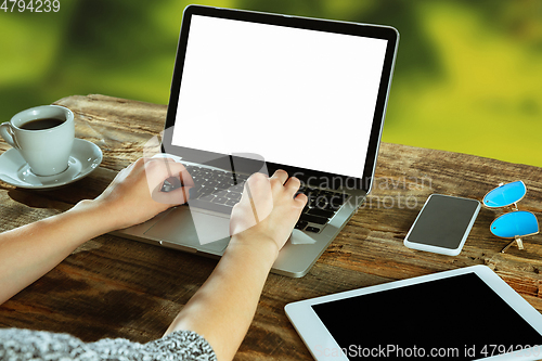 Image of Blank laptop on a wooden table outdoors, mock up