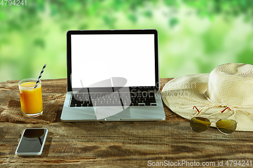 Image of Blank laptop on a wooden table outdoors, mock up