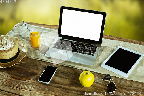 Image of Blank laptop on a wooden table outdoors, mock up