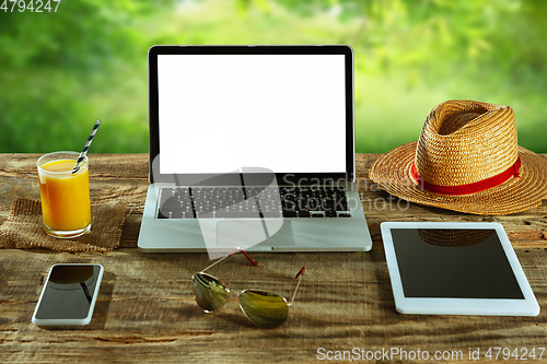 Image of Blank laptop on a wooden table outdoors, mock up