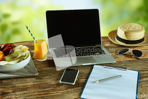 Image of Blank laptop on a wooden table outdoors, mock up