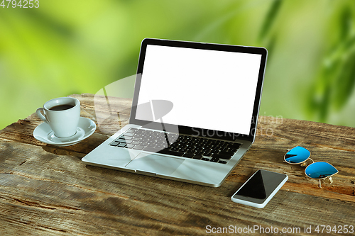 Image of Blank laptop on a wooden table outdoors, mock up