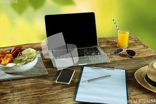 Image of Blank laptop on a wooden table outdoors, mock up