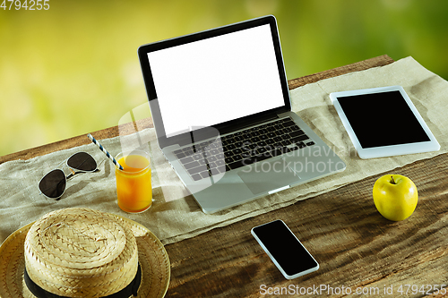 Image of Blank laptop on a wooden table outdoors, mock up