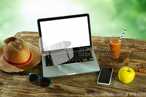 Image of Blank laptop on a wooden table outdoors, mock up