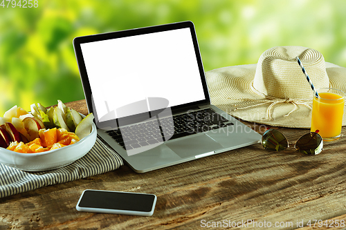 Image of Blank laptop on a wooden table outdoors, mock up