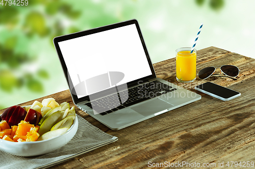 Image of Blank laptop on a wooden table outdoors, mock up