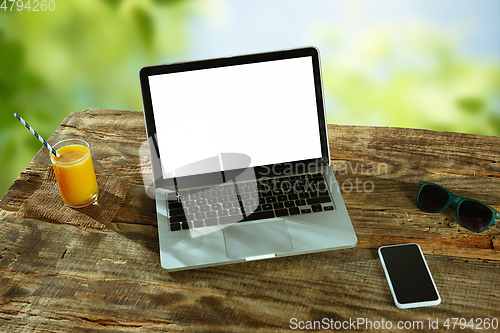 Image of Blank laptop on a wooden table outdoors, mock up