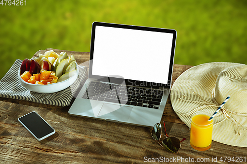 Image of Blank laptop on a wooden table outdoors, mock up