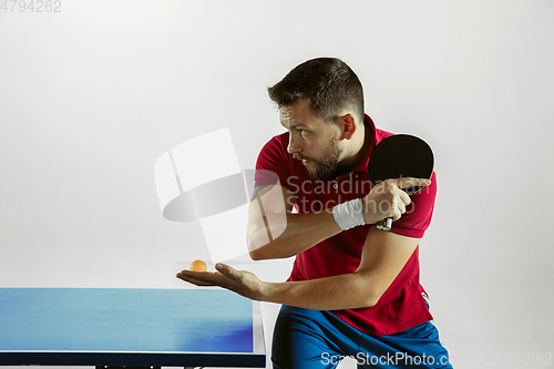 Image of Young man playing table tennis on white studio background