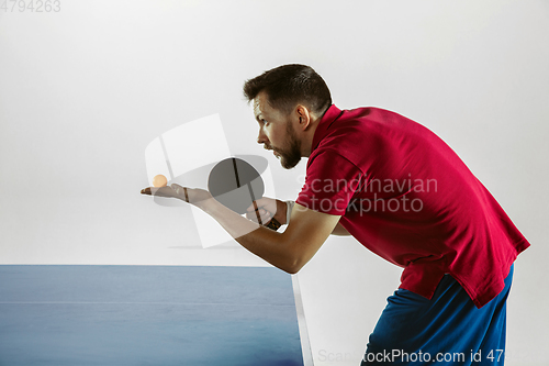 Image of Young man playing table tennis on white studio background