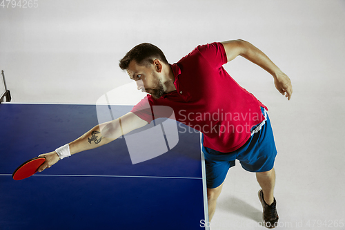 Image of Young man playing table tennis on white studio background