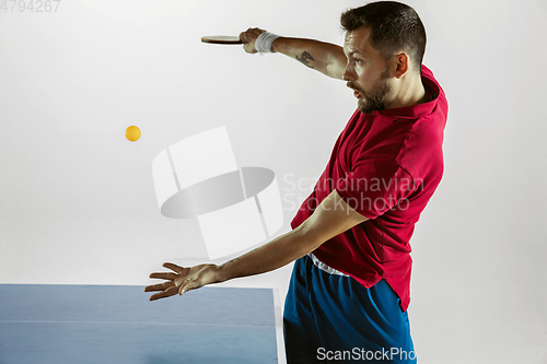 Image of Young man playing table tennis on white studio background