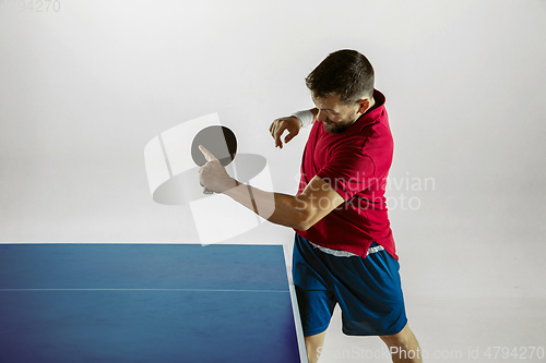 Image of Young man playing table tennis on white studio background