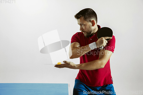 Image of Young man playing table tennis on white studio background