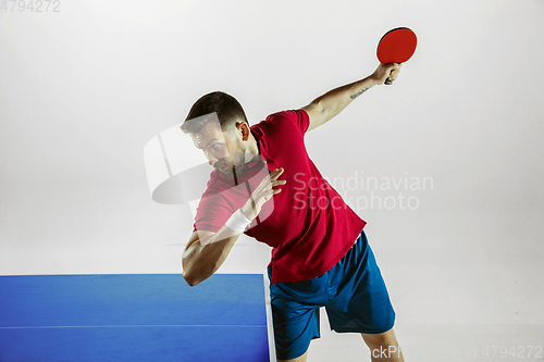 Image of Young man playing table tennis on white studio background