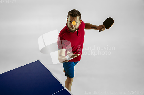 Image of Young man playing table tennis on white studio background