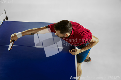 Image of Young man playing table tennis on white studio background