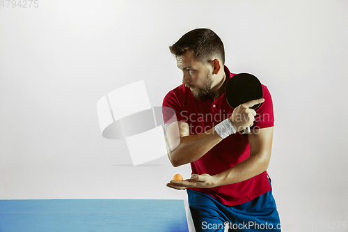 Image of Young man playing table tennis on white studio background