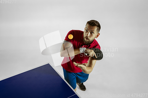 Image of Young man playing table tennis on white studio background