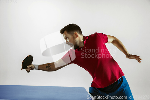 Image of Young man playing table tennis on white studio background