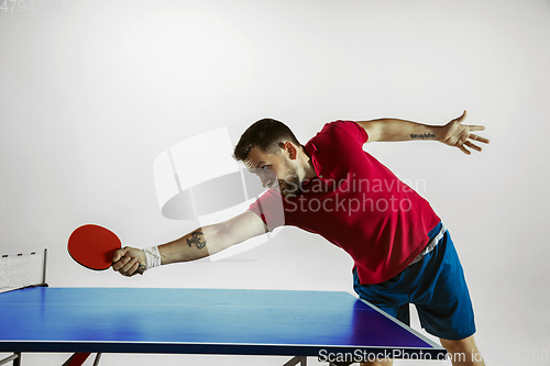 Image of Young man playing table tennis on white studio background