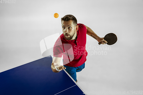 Image of Young man playing table tennis on white studio background