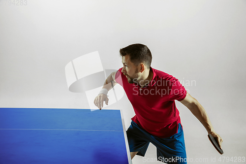 Image of Young man playing table tennis on white studio background