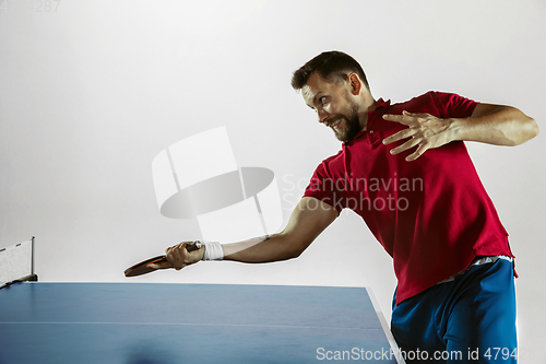 Image of Young man playing table tennis on white studio background