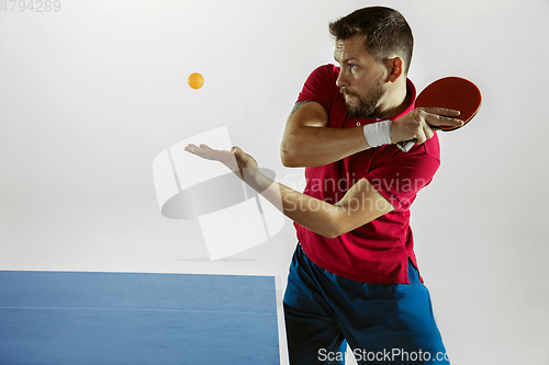 Image of Young man playing table tennis on white studio background