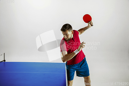 Image of Young man playing table tennis on white studio background
