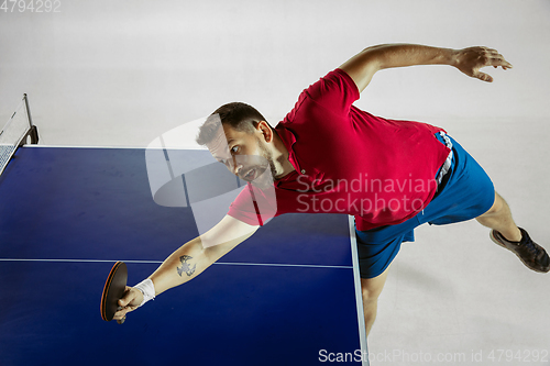 Image of Young man playing table tennis on white studio background