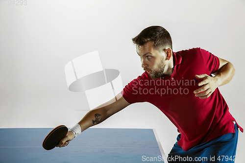 Image of Young man playing table tennis on white studio background